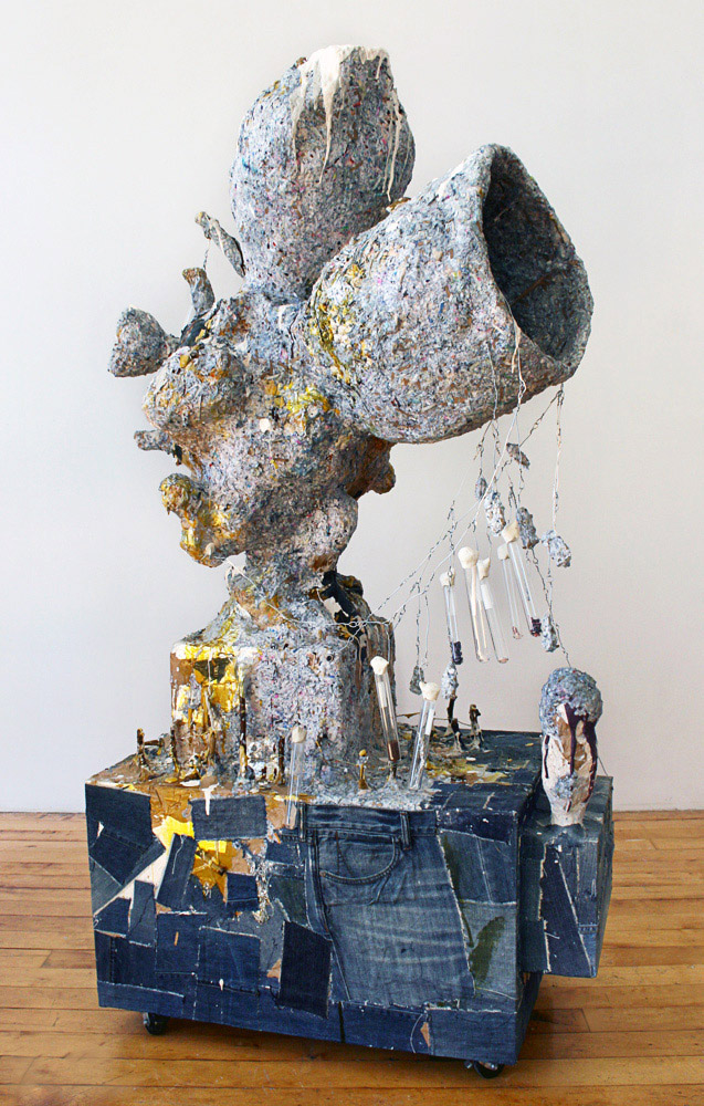 Randy Wray, Accelerator, 2011. Papier-mâché, wood, denim, test tubes, quartz crystals, wire, coins, buttons, acrylic paint, oil paint, glitter, resin. 64 x 34 x 25 in.