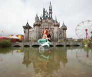 A mermaid piece by Banksy, with a castle by Banksy and Block 9 in the background, during the press view for the artistâs biggest show to date, entitled 'Dismaland', at Tropicana in Western-super-Mare, Somerset.